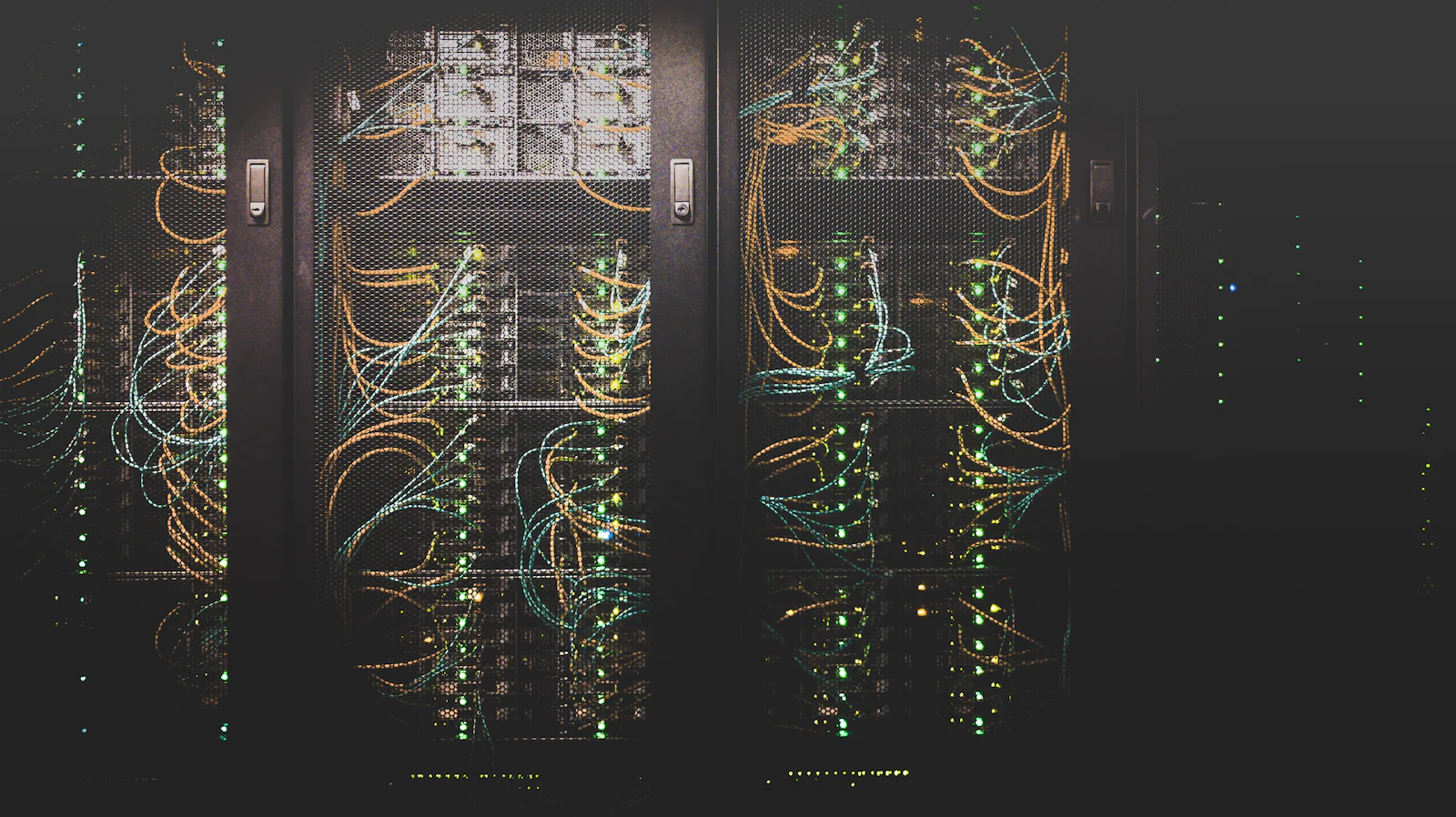 Corredor de um centro de dados com racks de servidores iluminados em baixa luz